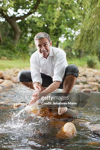 man washing hands in stream - roll shirt stock pictures, royalty-free photos & images
