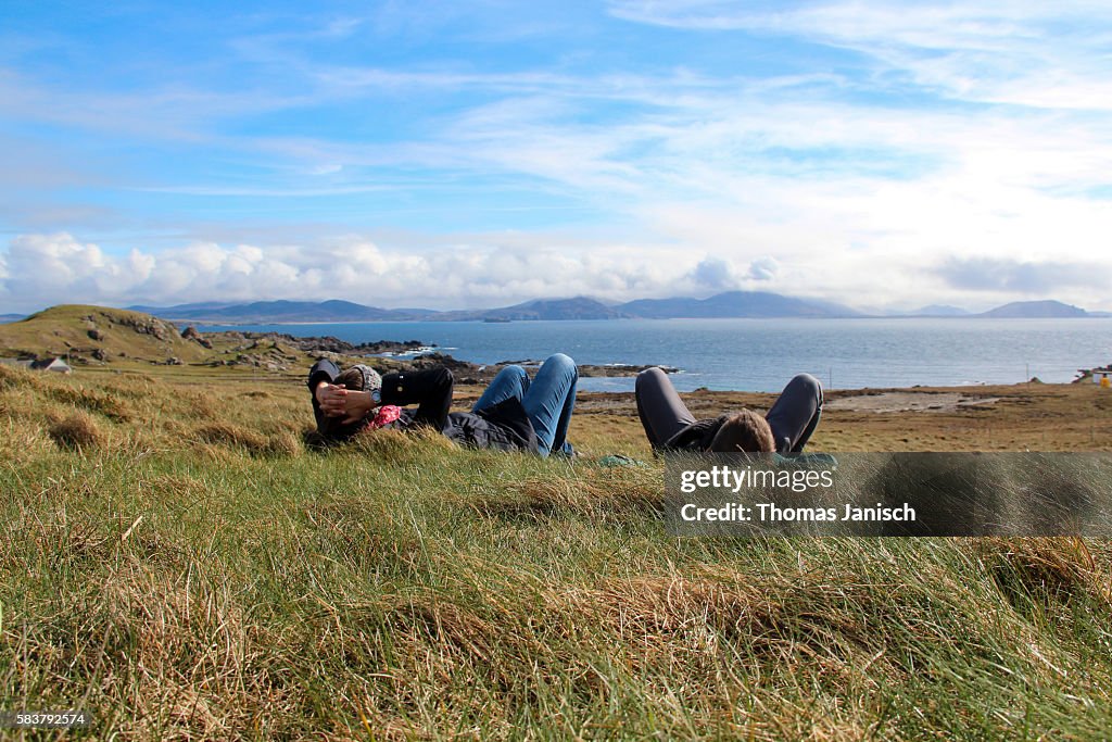 Lying in the grass and enoying the view of the rugged landscape around Malin Head, Ireland