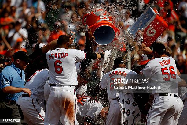 Nolan Reimold of the Baltimore Orioles is swarmed by his teammates at home plate after hitting a two run walk-off home run in the ninth inning to...