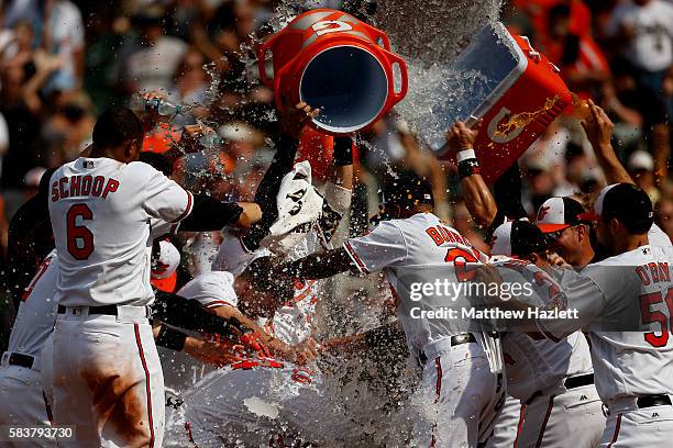 Nolan Reimold of the Baltimore Orioles is swarmed by his teammates at home plate after hitting a two run walk-off home run in the ninth inning to...