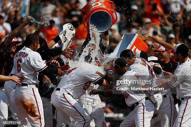 Nolan Reimold of the Baltimore Orioles is swarmed by his teammates at home plate after hitting a two run walk-off home run in the ninth inning to...