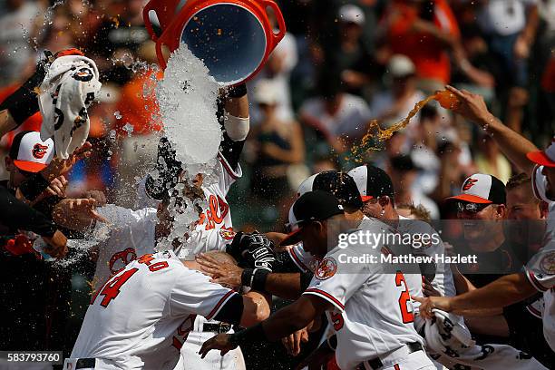 Nolan Reimold of the Baltimore Orioles is swarmed by his teammates at home plate after hitting a two run walk-off home run in the ninth inning to...