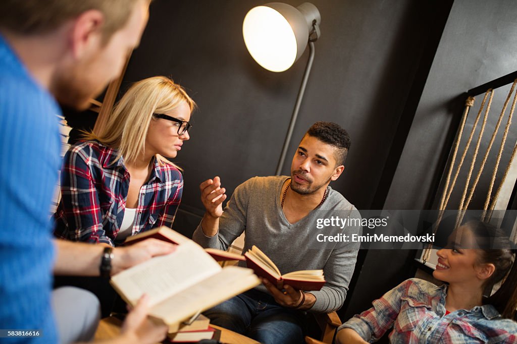 Diverse group of friends discussing a book in library.