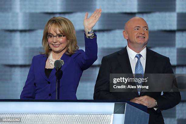 Former Congresswoman Gabby Giffords waves to the crowd as her husband, retired NASA Astronaut and Navy Captain Mark Kelly, looks on after delivering...