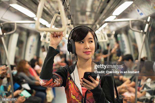 young woman listening to music while commuting - persoon luisteren muziek oortjes stockfoto's en -beelden