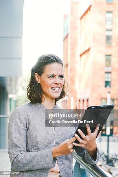 portrait of successful businesswoman using tablet in urban landscape - amsterdam zuidas stock pictures, royalty-free photos & images