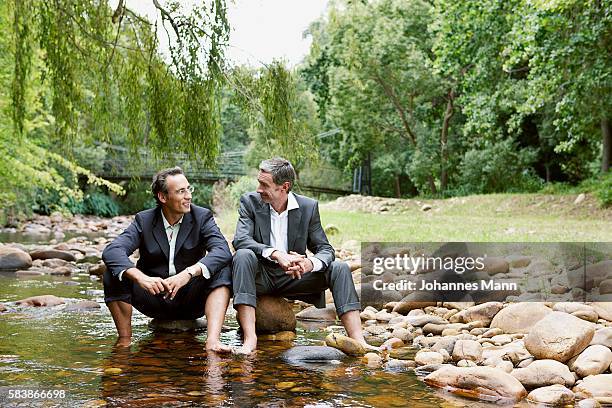 businessmen soaking feet in stream - green suit stock-fotos und bilder