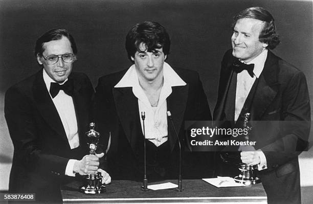 American actor and screenwriter Sylvester Stallone, with producers Irwin Winkler , and Robert Chartoff , receive the Best Picture award for their...