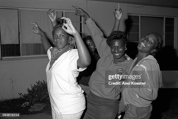 Young women affiliated with the Grape Street Crips pose "throwing" the gangs signature 'G' and 'W' hand signs. The Grape Street Watts Crips are a...