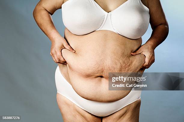 lady holding belly - dicker bauch stock-fotos und bilder