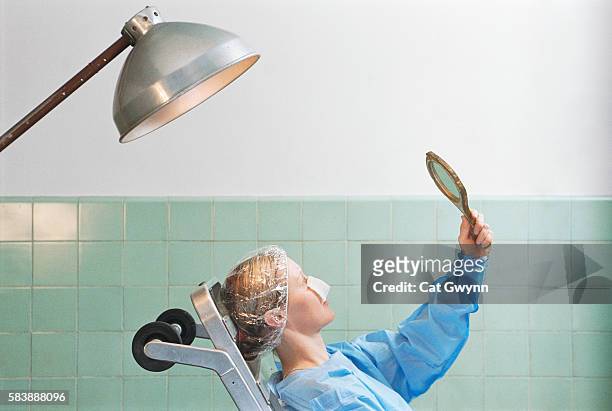 woman inspecting plastic surgery with mirror - reconstruction stock-fotos und bilder