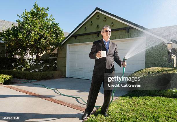 businessman watering lawn in business suit - garden hose foto e immagini stock