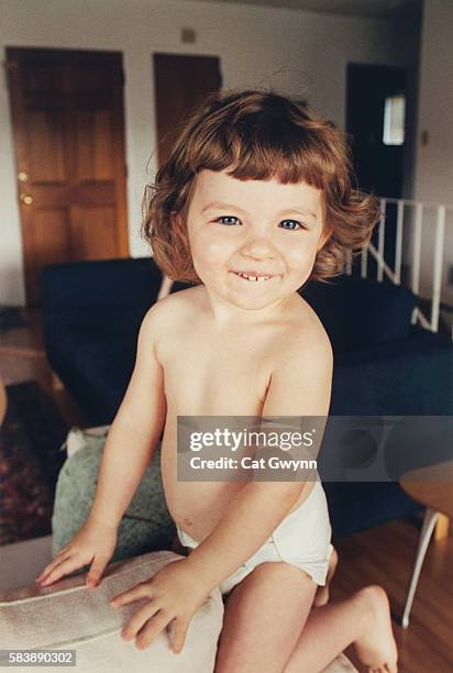 little girl kneeling on sofa arm - girl wearing diapers stock pictures, royalty-free photos & images