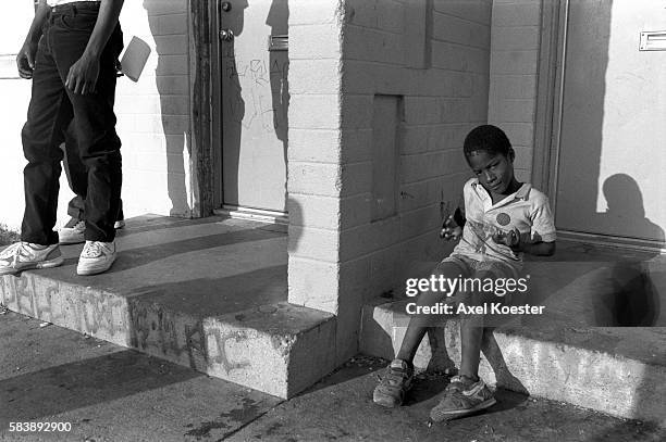 Young boy shows off what he has learned from his elder brothers hanging out on the stoop of his family's apartment. The Grape Street Watts Crips are...