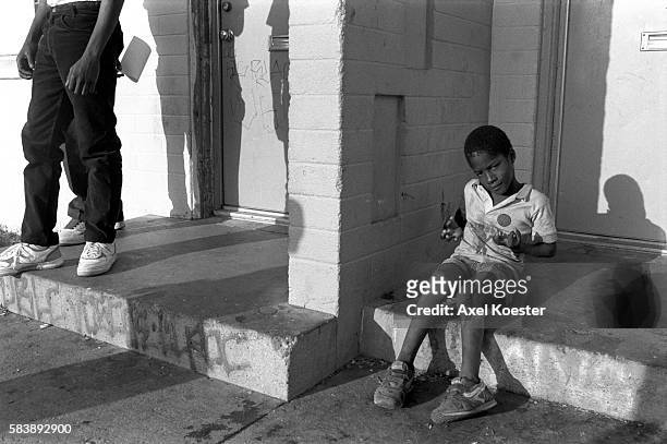 Young boy shows off what he has learned from his elder brothers hanging out on the stoop of his family's apartment. The Grape Street Watts Crips are...