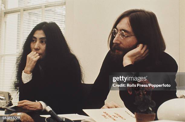 John Lennon of The Beatles pictured with his wife Yoko Ono in the Apple offices in London circa 1969. A copy of Wlhelm Reich's book 'The Murder of...