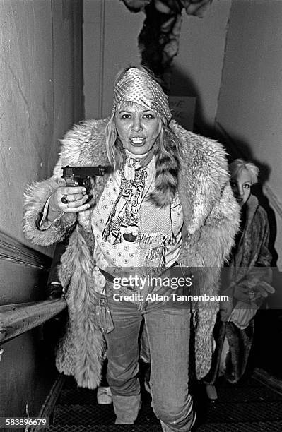 Model Anita Pallenberg holds handgun as she a climbs the stairs to the VIP room at the Mudd Club, New York, New York, February 10, 1980.