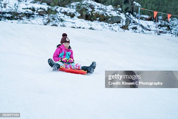 girl on toboggan sliding down on snow - snowcapped mountain stock pictures, royalty-free photos & images