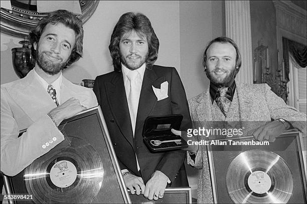 At Gracie Mansion for an awards ceremony and luncheon, music group the Bee Gees, Robin, Barry, and Maurice Gibb, pose with gold records and the Key...