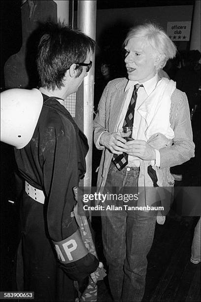 American author Victor Bockris, dressed as an MP, talks with Pop artist Andy Warhol at the Mudd Club's 'Combat Love' event, New York, New York, June...