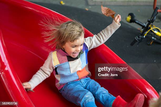 boy (4-5) on red slide - slide stock-fotos und bilder