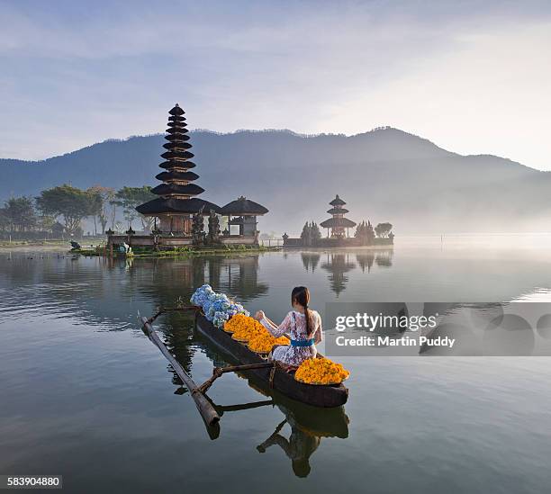 bali, woman rowing boat infront of ulun danu bratan temple - bratansee stock-fotos und bilder