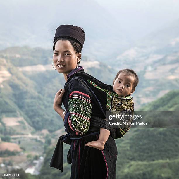 woman of the black hmong hill tribe carrying baby on her back - hmong stockfoto's en -beelden