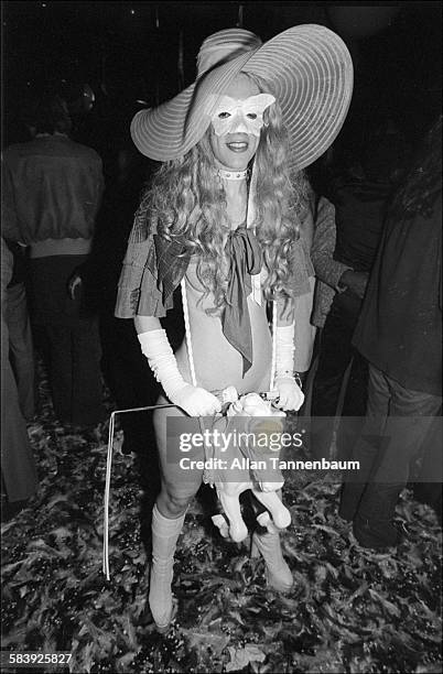 Portrait of a nearly naked woman, dressed in gloves, a short cape, mask, and hat, who also 'wears' a toy horse between her legs at Studio 54 during...