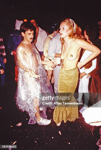 Man, dressed only in a clear plastic sheet, dances with a topless woman at a Studio 54 Halloween party, New York, New York, October 31, 1978.