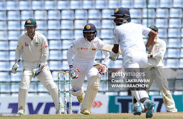 Sri Lanka's Dhananjaya de Silva runs between the wickets as Australian wicketkeeper Peter Nevill looks on during the third day of the opening Test...