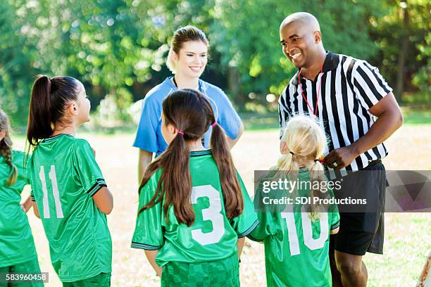 youth soccer referee explains game rules to players - huddle sport girls stock pictures, royalty-free photos & images