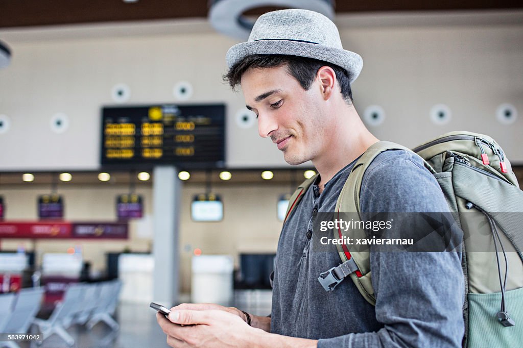 Young man with backpack and cell phone in airport
