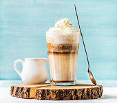 Latte macchiato with whipped cream, serving silver spoon and pitcher