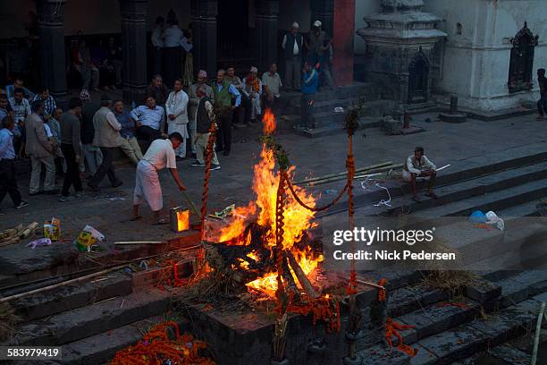 men watching cremation fire at pashupatinath - feuerbestattung stock-fotos und bilder