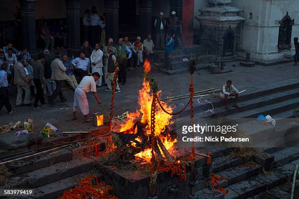 men watching cremation fire at pashupatinath - crémation photos et images de collection