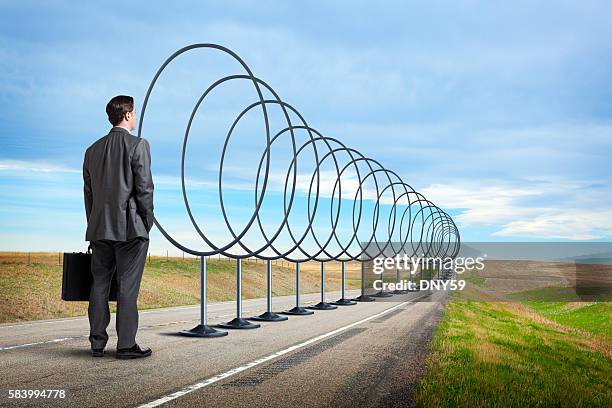 businessman looking down road lined with hoops to jump through - jumping through hoops stock pictures, royalty-free photos & images