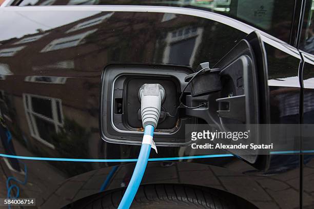 battery charger in the black electric car - electric car charger imagens e fotografias de stock