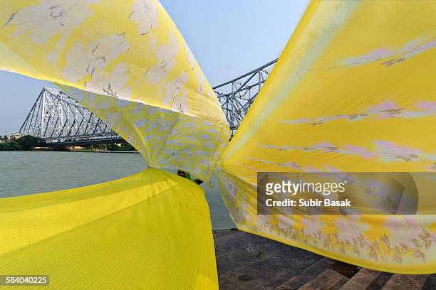 woman drying sarees and on the bank of river ganga - howrah bridge stock pictures, royalty-free photos & images