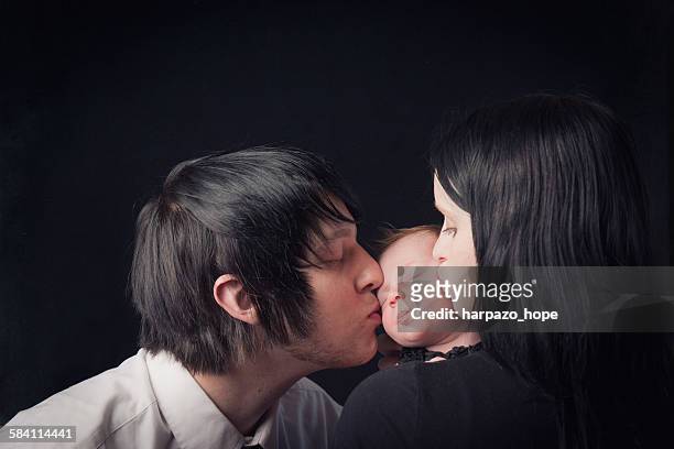 parents kissing their newborn's cheeks - goth photos et images de collection