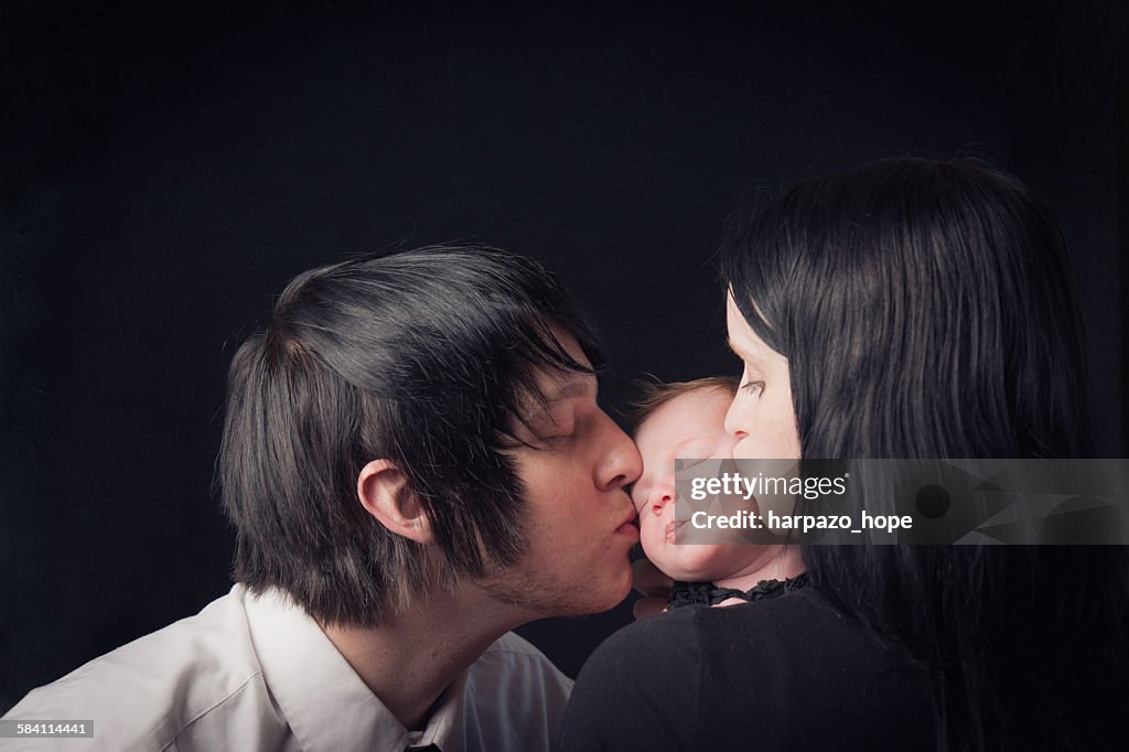Parents kissing their newborn's cheeks