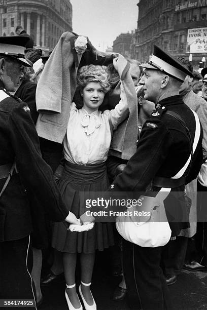 Young woman uses her coat to protect her coiffured hair from the rain during the Victory Day parades in London, 8th June 1946. Original Publication:...