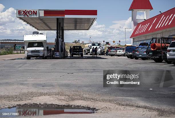 Exxon signage is reflected in a puddle as customers put fuel in their vehicles at a roadside Exxon gas station outside Aurora, New Mexico, U.S., on...