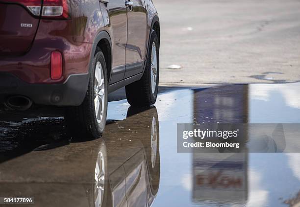 Exxon signage is reflected in a puddle at a roadside Exxon gas station outside Aurora, New Mexico, U.S., on Tuesday, July 26, 2016. Exxon Mobil Corp....