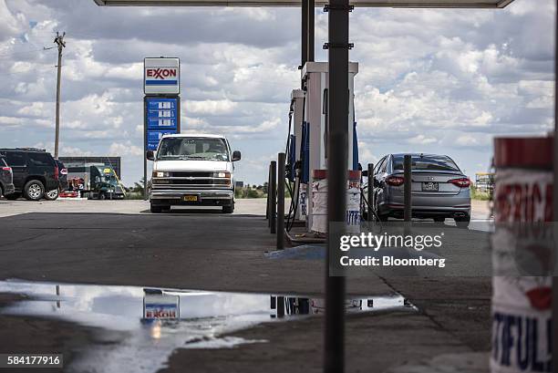 Exxon signage is reflected in a puddle at a roadside Exxon gas station outside Aurora, New Mexico, U.S., on Tuesday, July 26, 2016. Exxon Mobil Corp....