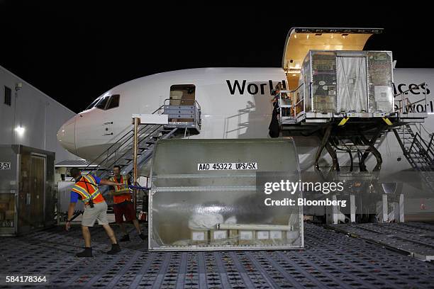 Workers pull package containers to be unloaded during the night package sort at the United Parcel Service Inc. Worldport facility in Louisville,...