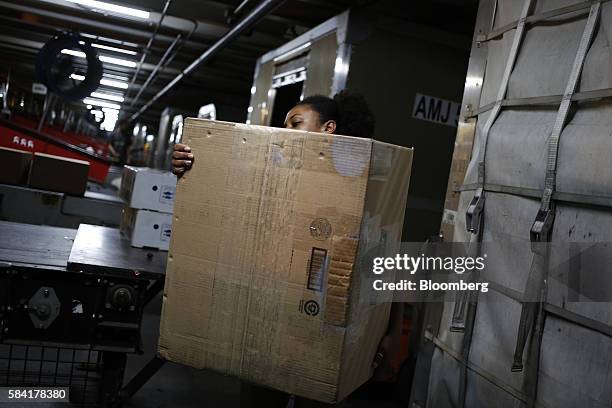 Worker unloads packages from a container during the night package sort at the United Parcel Service Inc. Worldport facility in Louisville, Kentucky,...