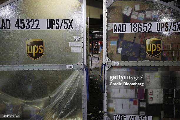 Package containers sit before being unloaded during the night package sort at the United Parcel Service Inc. Worldport facility in Louisville,...