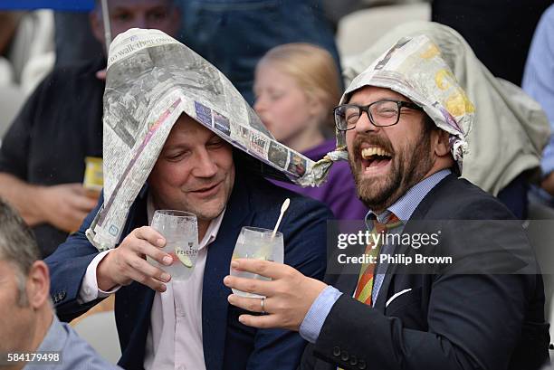 Two spectators enjoy themselves as rain delayed the start of the Natwest T20 Blast match between Middlesex and Essex at Lord's cricket ground on July...