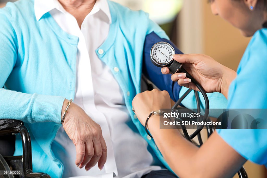 Senior woman in wheelchair getting her blood pressure taken