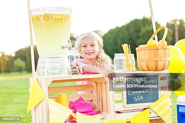 sweet little girl sitting behind her lemonade stand - girl who stands stock pictures, royalty-free photos & images